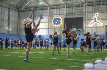 Dance team rehearses alongside band on Carolina practice field.