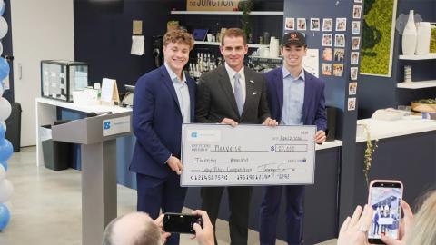 three men hold a giant check