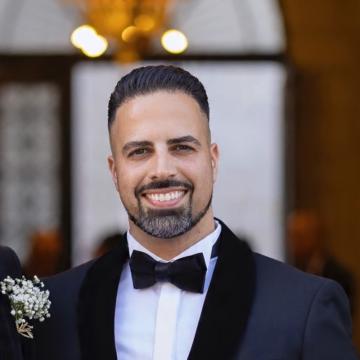 A person wearing a bow tie smiles for a portrait.