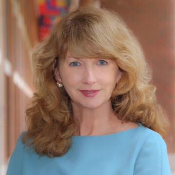 A person with long blonde hair poses for a portrait. 