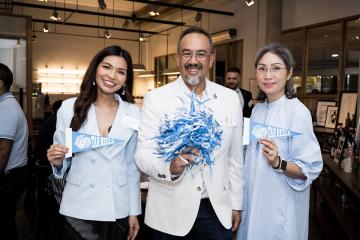 Three people holding up Tar Heel pennants and a pom-pom at an event