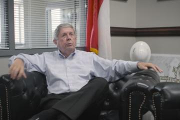 Person sits in a leather chair talking to someone off screen.