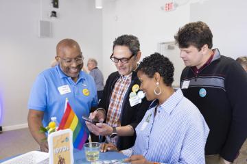 Alumni gather around a smartphone to look at pictures at CPAN Spring Reunion Weekend