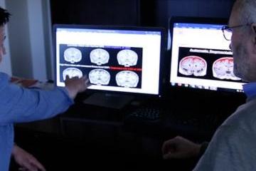 Joseph Piven and colleague look at brain scans on computers.&nbsp;