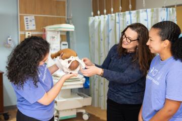 Three doula scholars demonstrate holding a baby