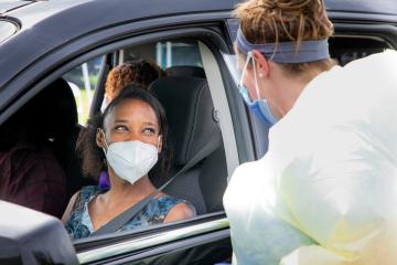 UNC Mobile Health Clinic staff talk to a person in a car while wearing masks