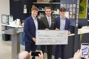 three men hold a giant check