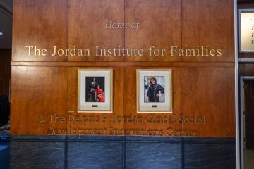 Wall that reads "Home of The Jordan Institute for Families" with two portraits beneath.
