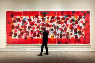 John Townsend walking in front of a large red painting in the Ackland Art Museum