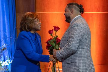 Deloris P. Jordan hands a rose to Marc Velasquez.