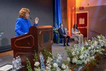 Deloris P. Jordan stands on a stage and speaks at a podium.