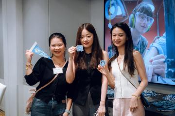Three Tar Heels hold up UNC branded items at an event in Singapore