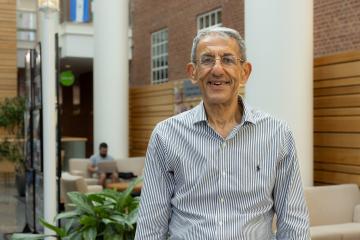 Professor Ibrahim smiling at the camera in the lobby of Gillings on U.N.C. campus.