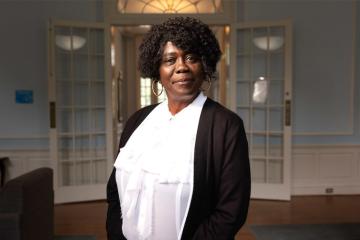 Robin Lee smiles in front of an open doorway in residence hall lounge.