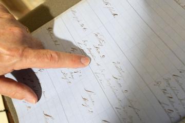 A finger skims the page of a 19th-century doctors' notes in a daybook from the Wilson Special Collections Library