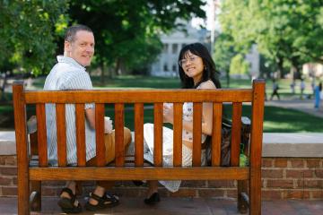 Bob Goldstein and TK Pham sitting on a bench with coffees