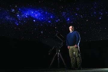 Nicholas Law, head of the Argus Array project, poses with a telescope beneath the Milky Way