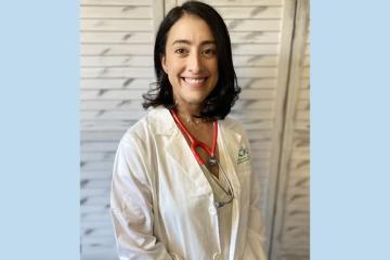 Craven poses for a portrait wearing a doctor's coat and a stethoscope hanging over her shoulders.