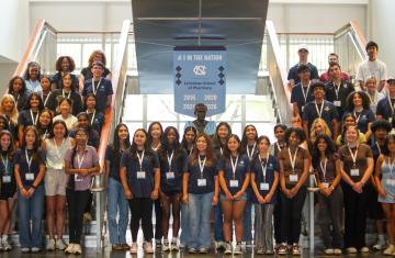 Participants stand in the lobby of an academic building and pose together.