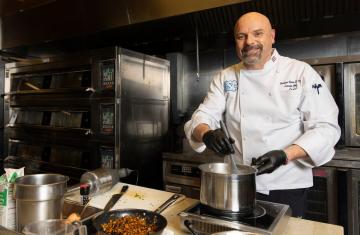 Executive Chef Christian Chiron cooking in the kitchen of Lenoir Dining Hall.