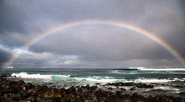 A rainbow stretches across Punta Carola Beach in San Cristobal, Galapagos.
