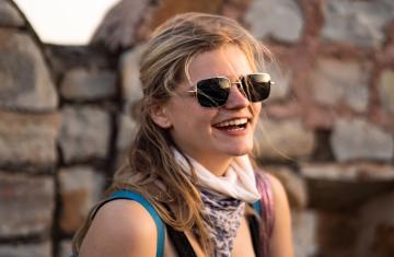 Chandler Simpson stands in front of a brick wall, smiling in sunglasses.