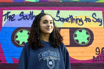 Haillie Brew smiles in front of a colorful mural that reads 'The South Has Something to Say.
