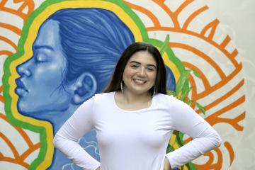 Peyton Brooks smiles in front of a colorful mural.