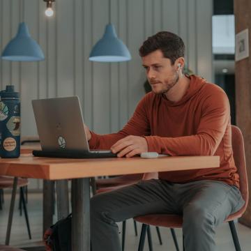 Drew Stockton typing on a laptop in a cafe