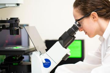 Alison Mercer-Smith looking into a microscope in a lab