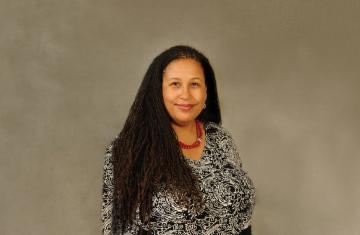 A portrait of Naomi Andre facing the camera on a gray background