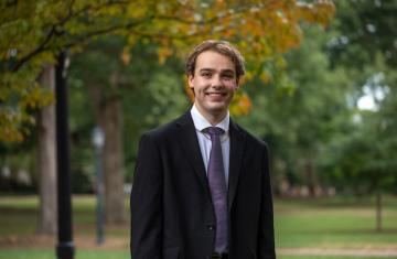Osman in a suit smiling.