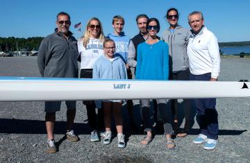 A group of people pose behind the Lady J rowing boat.