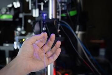 A hand holding a fiber optic cable in a lab.
