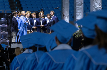 UNC Clef Hangers singing "Carolina in My Mind" in front of a microphone.