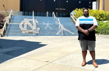 Shaun Anderson stands in the foreground with steps sporting UNC-Chapel Hill athletic branding in the background