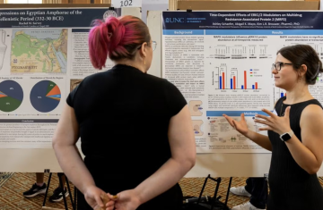 Person presents research poster to onlooker