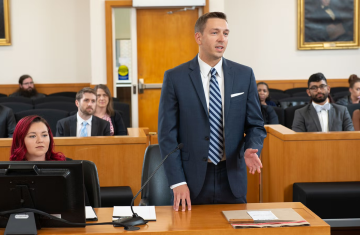 Person stands at a table in a court room