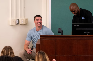 Person sits in a chair at the front of a lecture hall