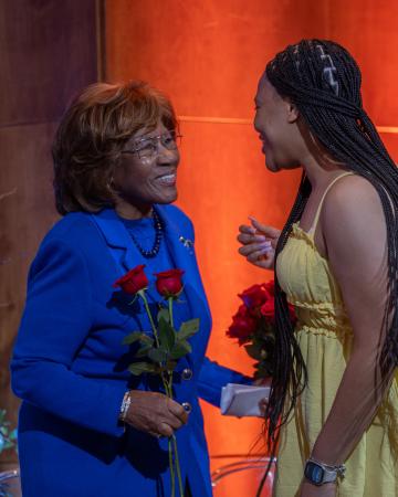 Scholarship recipient gives Deloris P. Jordan a flower on stage.