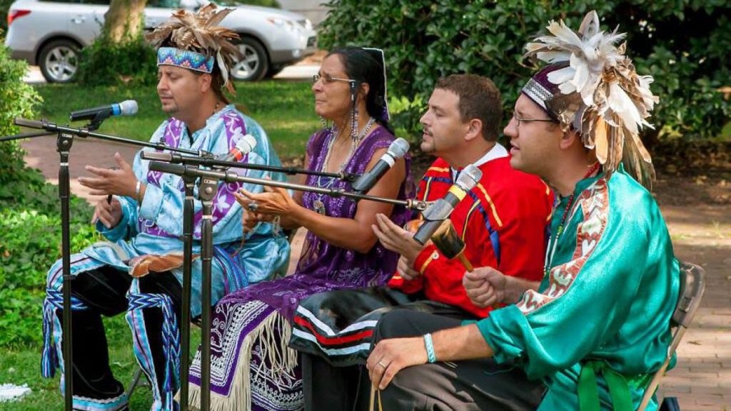 American Indian performers sing while dressed in traditional Native American clothing