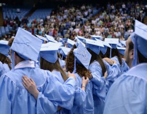 Graduating UNC-Chapel Hill students wearing regalia and with hands on each other's backs.