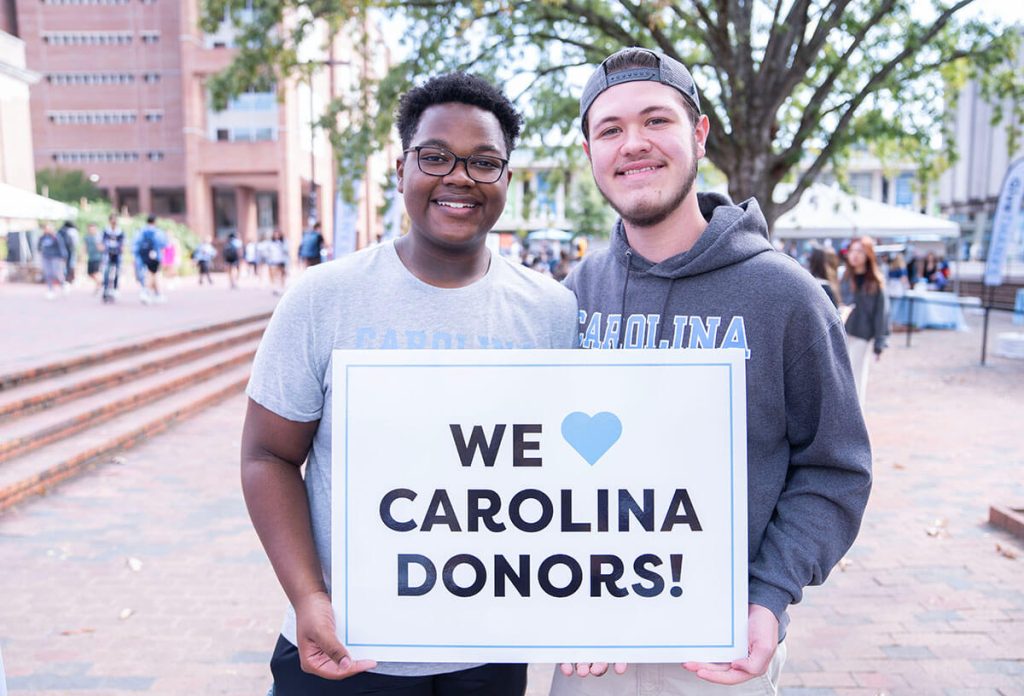 Carolina students hold up sign thanking donors at GiveTHANKS in the Pit on the UNC-CH campus