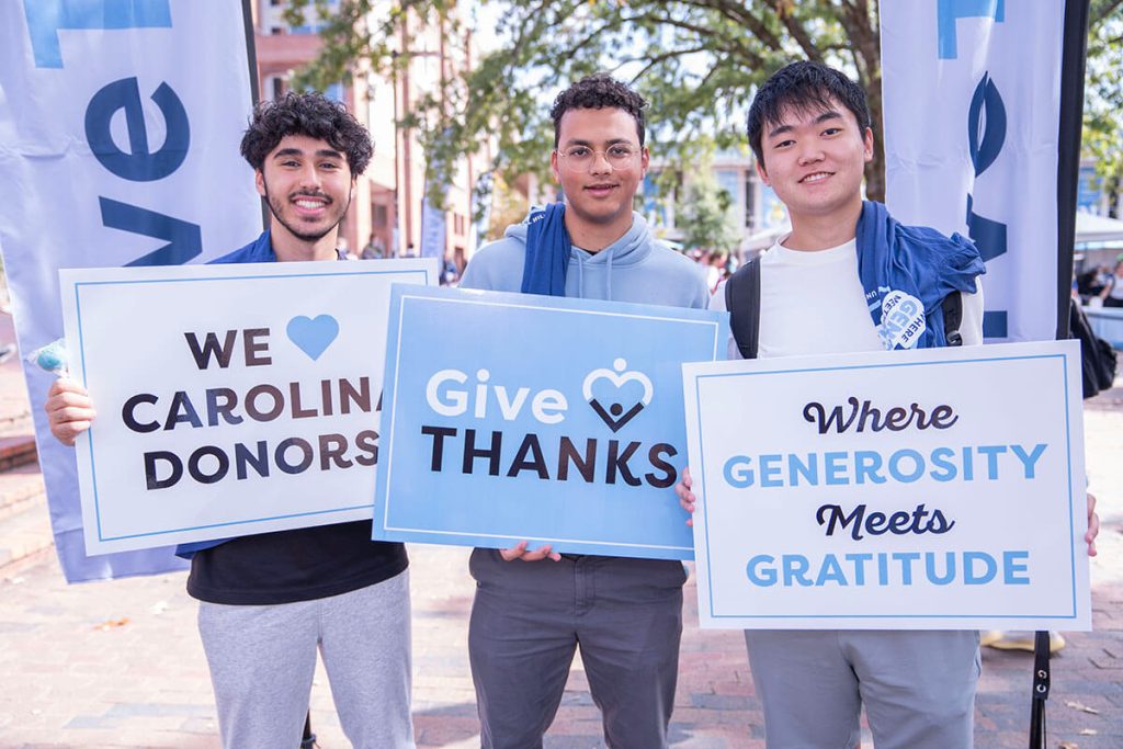 Carolina students hold up signs thanking donors at GiveTHANKS in the Pit on the UNC-CH campus